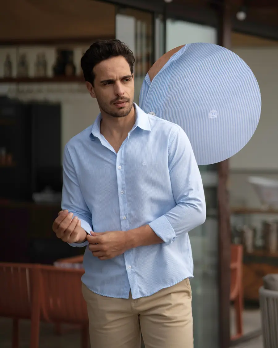 Homem ajustando a manga de uma camisa social azul-clara listrada