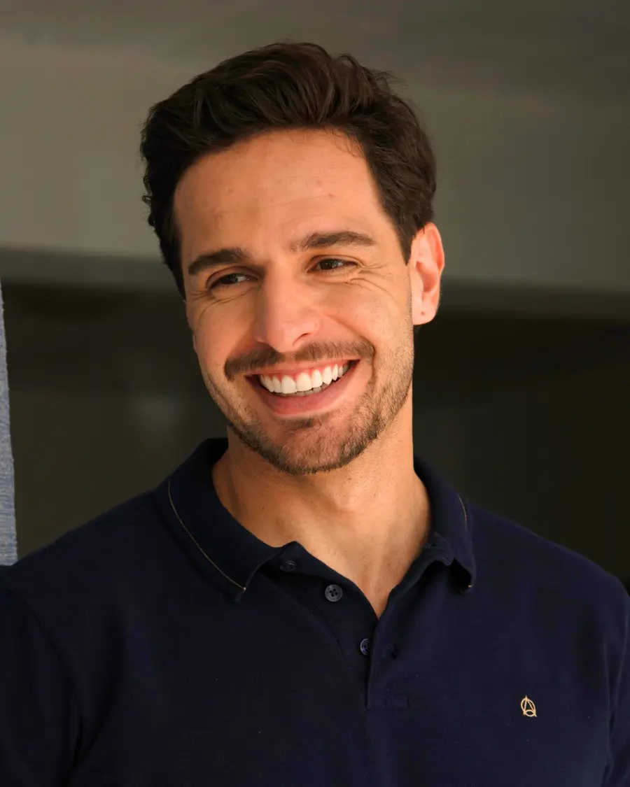 Homem sorrindo vestindo camisa polo azul-marinho com o símbolo da marca