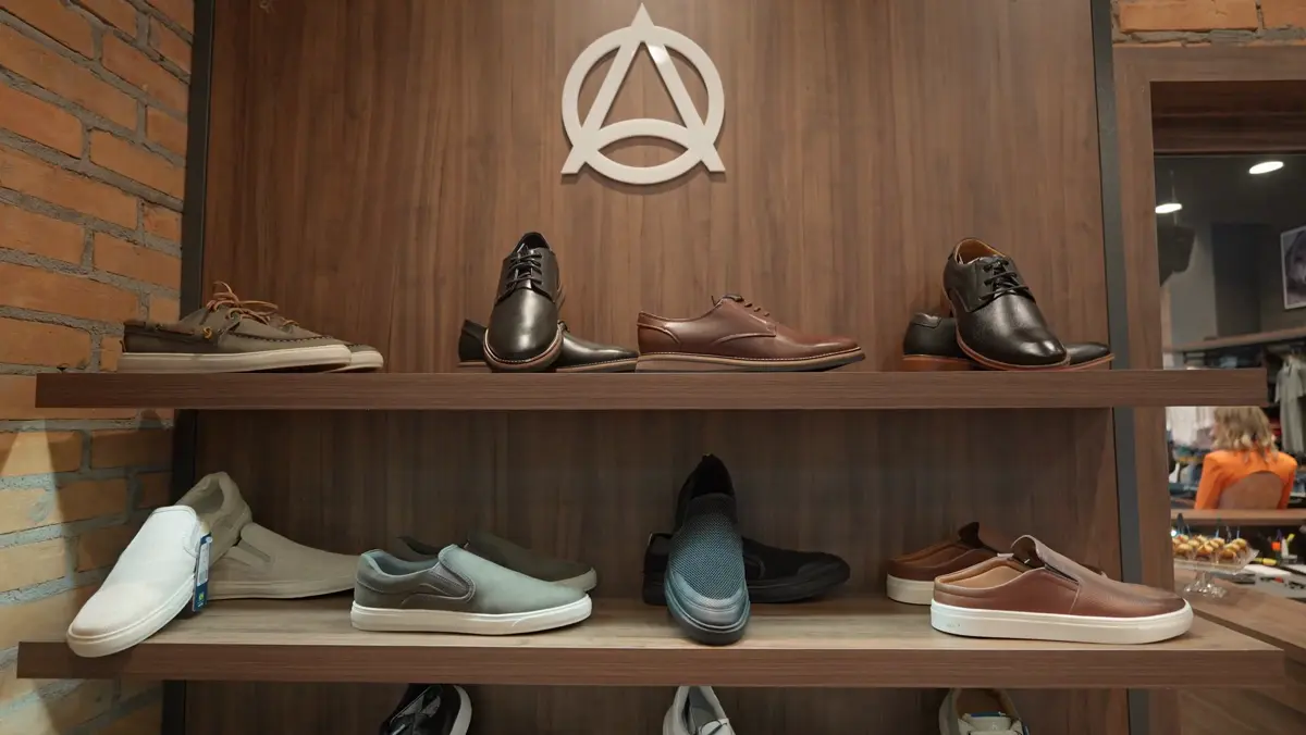 Prateleiras de madeira com sapatos e tênis masculinos sob o símbolo da marca